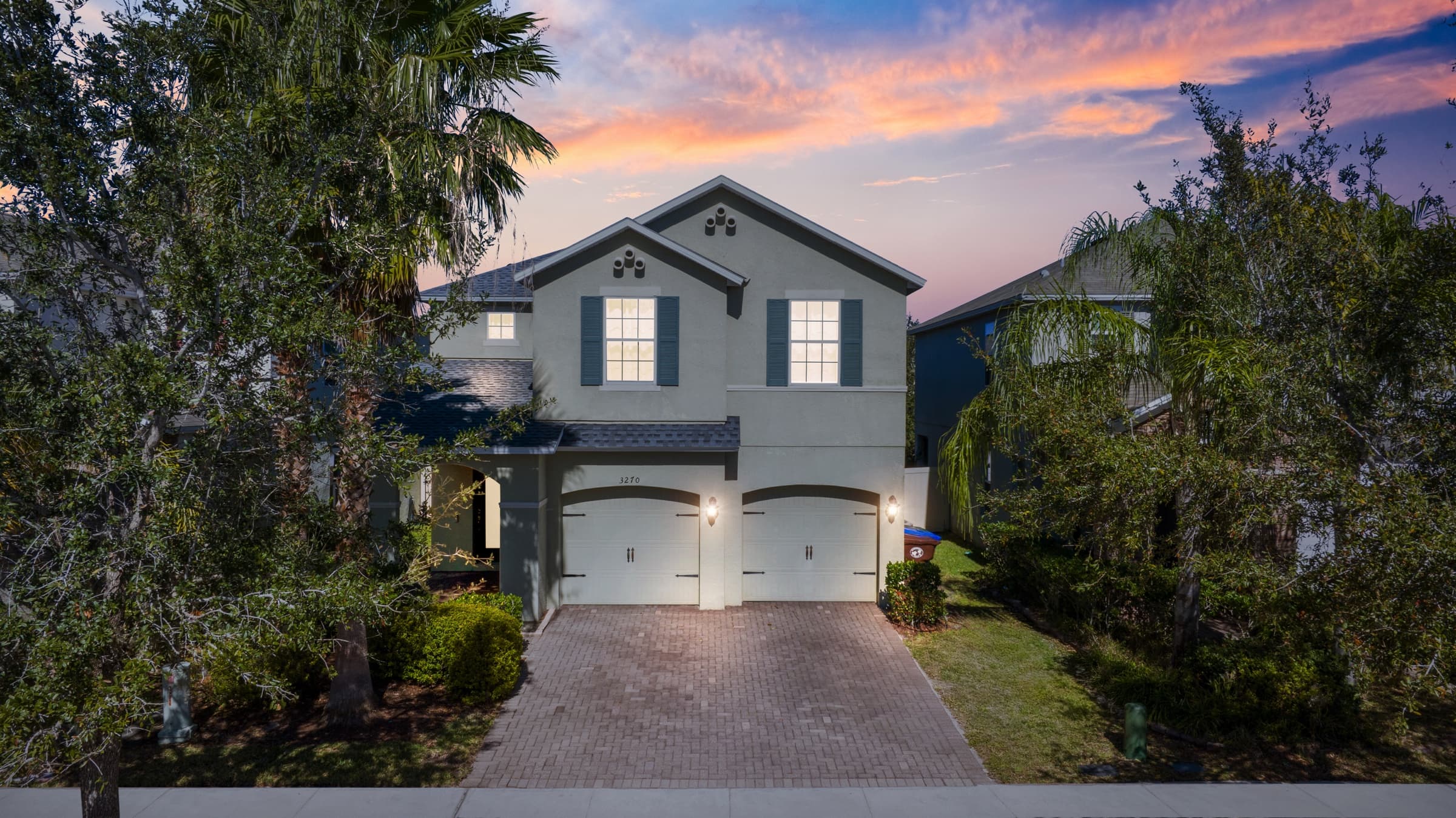 The same house converted to dusk: a soft evening sky, lit windows and glowing exterior lights