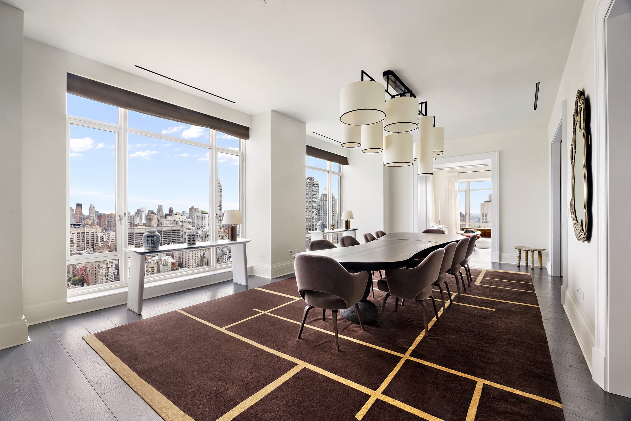 The same dining room after editing: bright natural daylight, clean white walls and a clear city view through the windows