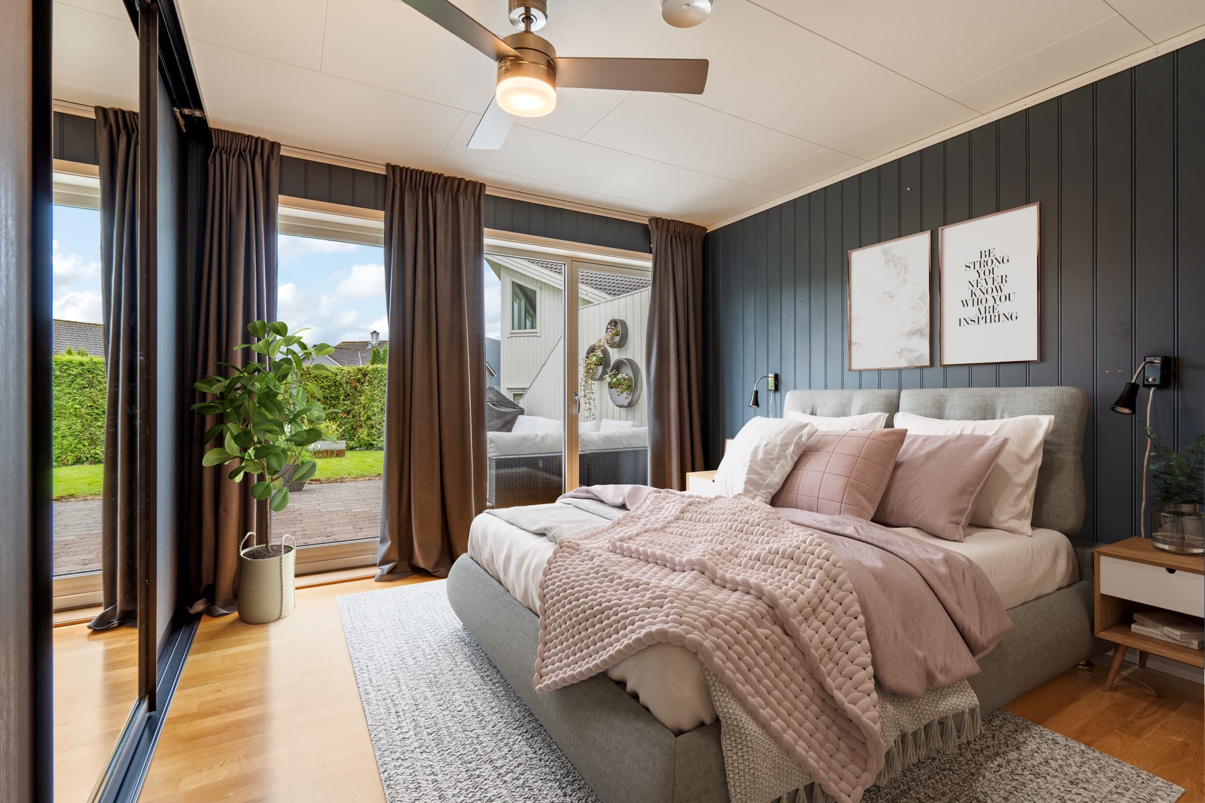 The same bedroom virtually staged with an upholstered bed, soft bedding, rug, plant and wall art