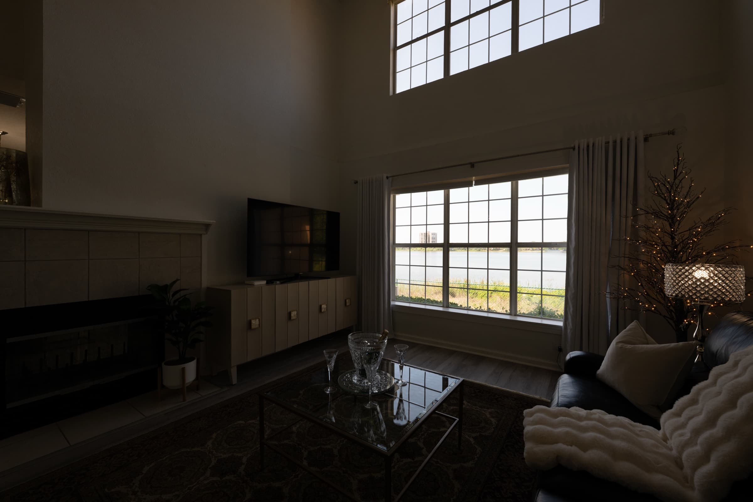 Dark, underexposed living room with a fireplace, TV and large windows, original unedited photo